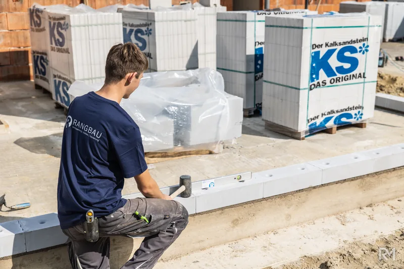 Maurer arbeitet an der ersten Steinreihe