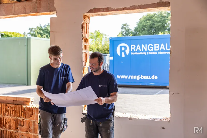 Zwei Handwerker mit Bauplan im Rohbau