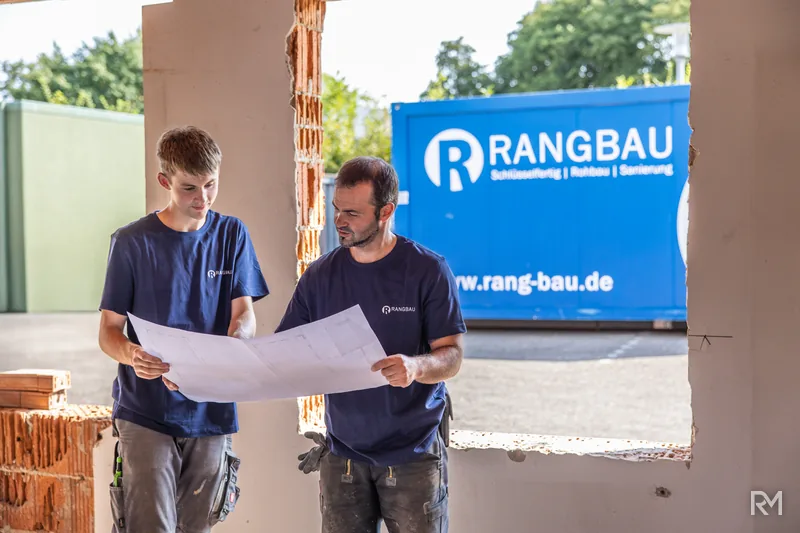 Zwei Handwerker im Durchgang des Rohbaus