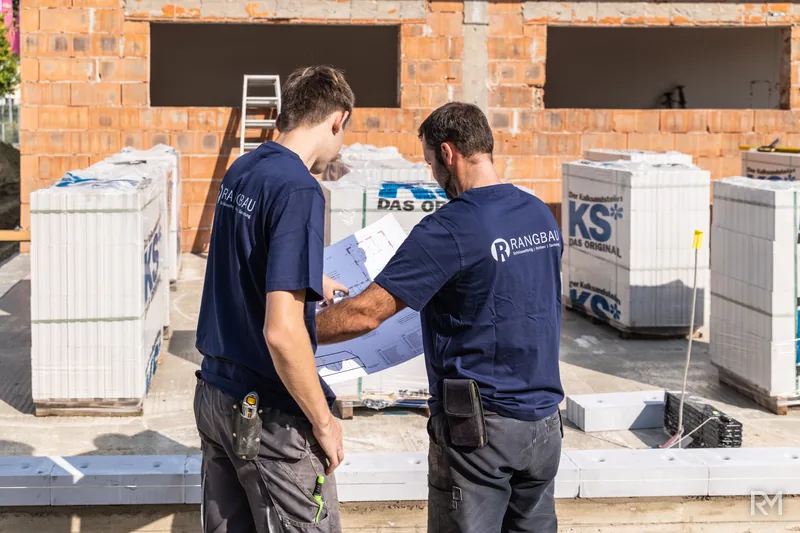Zwei Handwerker rollen den Bauplan aus